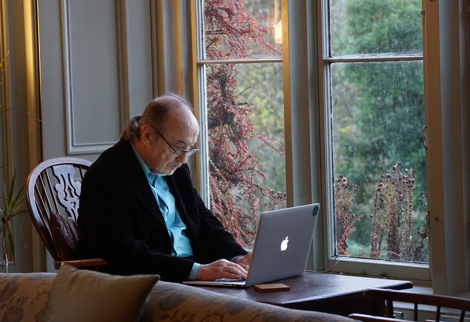 healthcare professional typing on a laptop computer with green stethoscope laying next to the laptop on the desk.